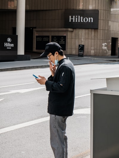 身穿黑色长袖衬衫和棕色裤子的男子白天站在灰色水泥路上